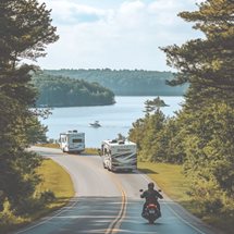 image of a motorcycle following two RVs on a trip