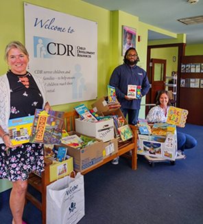 BFCU members posing with a several boxes full of books that they collected for Child Development Resources.